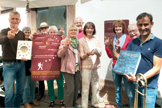 Menschengruppe mit Sternenwegplakat zeigt Victory-Zeichen