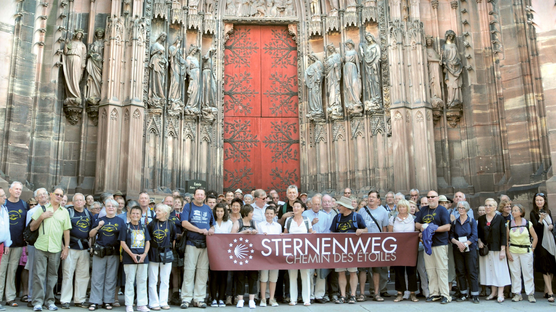 Group picture of pilgrims in front of Metz Cathedral with Starry Path banner