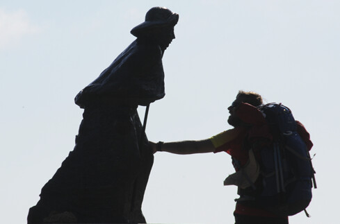 Pilger berührt Statue